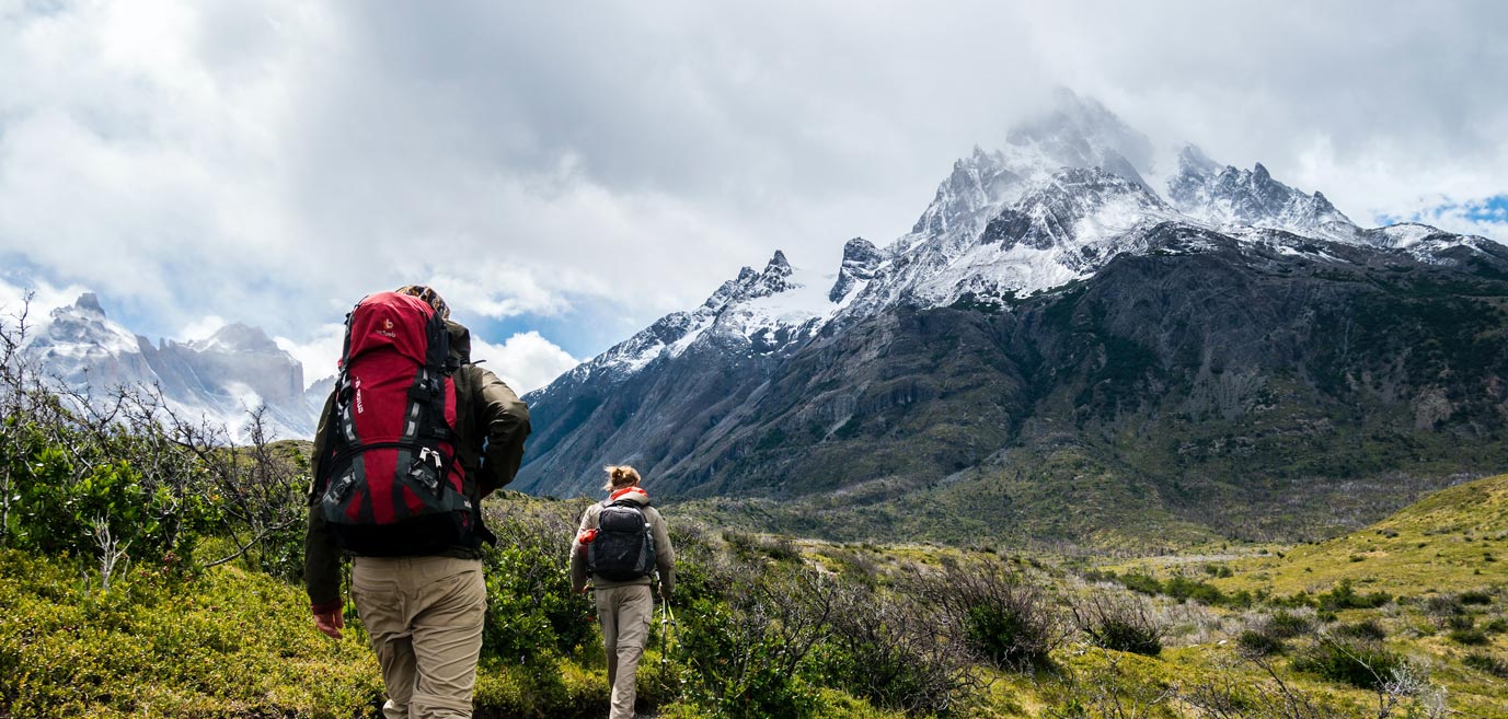 Two people hiking near a snowy mountain